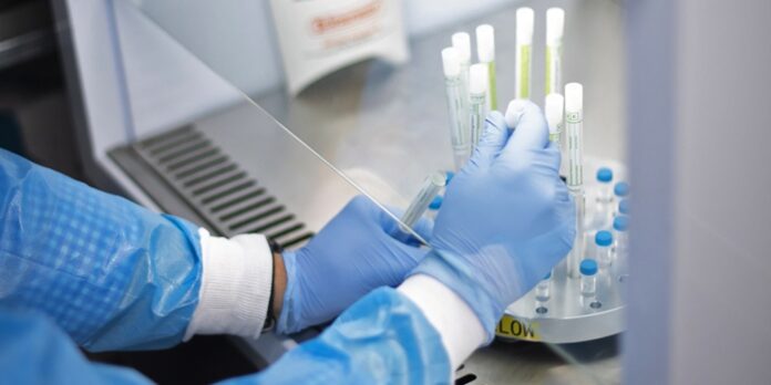 Hands in protective gloves performing laboratory analysis using mobile testing equipment for pandemic response and virus detection